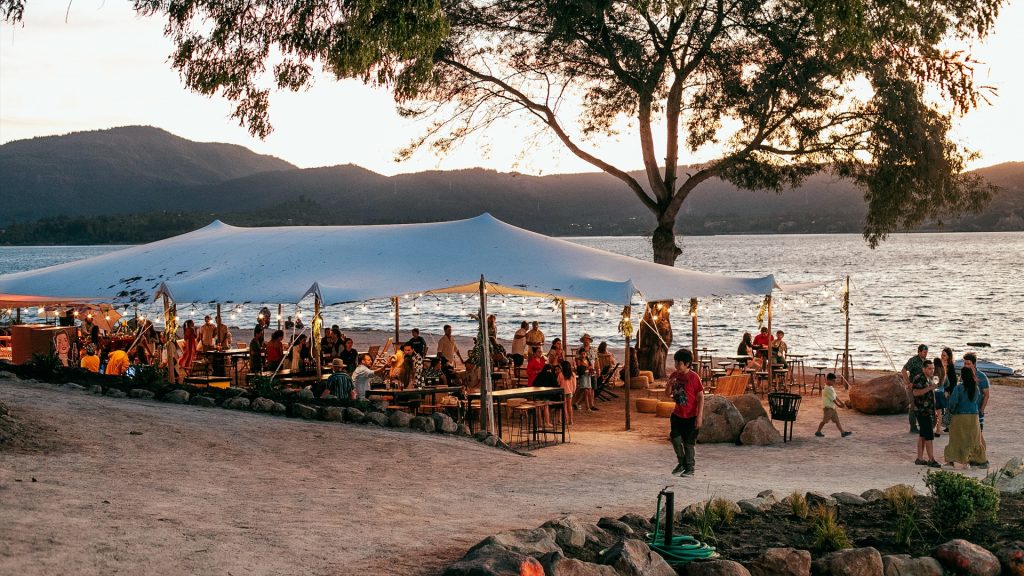 Personas compartiendo bajo un toldo en la playa, a orillas del Lago Colbún