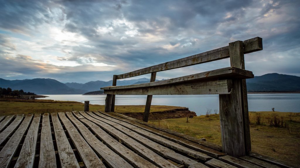 Banco y deck de madera frente a la orilla del Lago Colbún