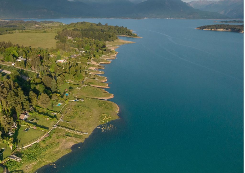Orilla de la ribera norte del Lago Colbún vista desde el aire, con el agua llegando a cada bahía